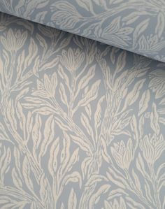 a blue and white wallpaper with leaves on it's side, next to a window