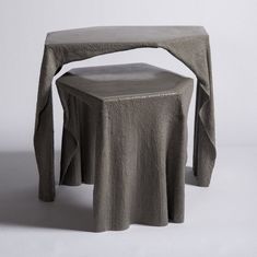 a small table with a gray cloth draped over it's top and the seat is made out of concrete