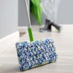 a blue and white crocheted duster sitting on the floor next to a green umbrella