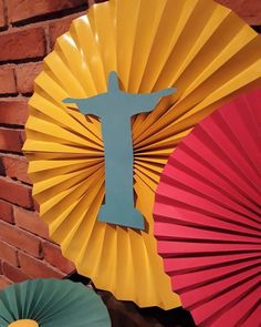 colorful paper fans with the image of jesus on them next to a red brick wall