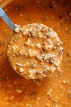 a ladle full of soup with a spoon sticking out of it's top