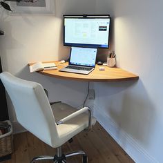 a laptop computer sitting on top of a wooden desk next to a white office chair