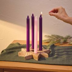 a person lighting three candles on a table