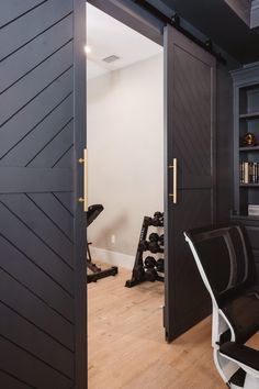 an open door to a home gym with black and white chairs in the corner,