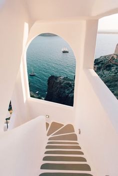 stairs leading up to the top of a white building with an ocean view in the background