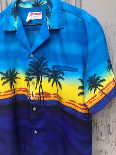 "Excellent vintage condition. No stains, no holes, no odors. Tag size M. Fits like a Men's roomy Medium. Laying flat: 22 1/2\" Pit to Pit 27\" Top to Bottom Awesome 70s tropical shirt by Shoreline, made in Hawaii. Super soft and lightweight button up shirt, made of polyester. Great for a hot day at the beach!" Blue Tropical Shirt For The Beach, Tropical Blue Shirt For The Beach, Tropical Blue Shirt For Beach, Blue Camp Shirt With Graphic Print For Beach, Printed Blue Camp Shirt For Beach Season, Blue Hawaiian Camp Shirt For Beach, Blue Printed Hawaiian Shirt For Summer, Blue Printed Camp Shirt For Beach Season, Blue Printed Summer Hawaiian Shirt