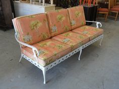 an orange and white couch sitting on top of a floor next to other furniture in a store