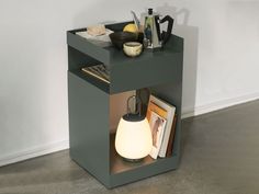 a small side table with a lamp on top and books in the bottom shelf next to it