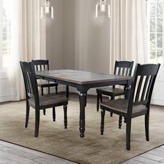 a dining room table with four chairs and a rug on the floor in front of it