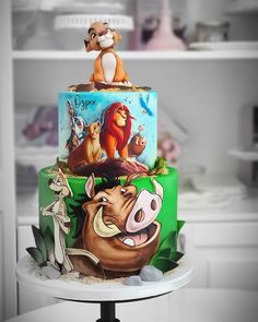 a three tiered cake decorated with the lion king and other disney characters on it