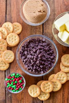 crackers, cheese and candy are arranged in bowls on a wooden table with other snacks