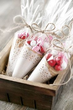 three candy cones wrapped in cellophane and tied with twine are sitting in a wooden box