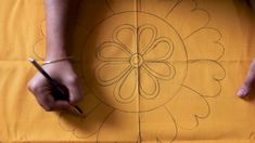 someone is drawing a flower on a piece of yellow paper with black marker and pen