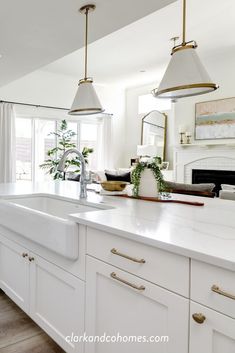 a kitchen with white cabinets and marble counter tops, gold pulls on the faucet