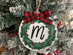 a christmas ornament hanging from a tree with the letter m on it's front