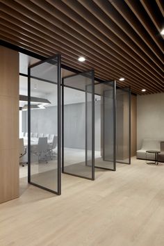 an empty office with glass walls and wood ceilinging is seen in this image from the inside