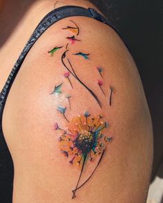 a woman's shoulder with a dandelion tattoo on it