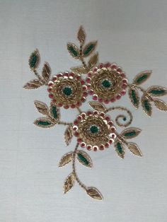 two brooches with green and red beads on them sitting on a white surface