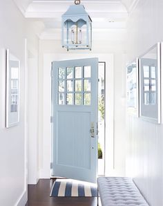 a blue front door with a bench in the hallway next to it and a light fixture hanging from the ceiling