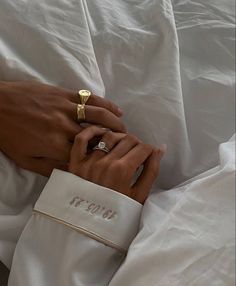 two hands holding each other while laying in bed