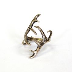 a silver ring with antlers on it sitting on a white surface, in the shape of a deer's head