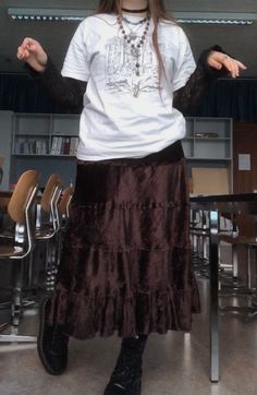 A mid-size person/girl wearing mate rose lipstick, a vintage graphic oversized shirt and a  black lace long sleeve underneath, a thrifted dark brown maxi skirt, black dr. Martens and multiple crystal rings and bracelets. The person is also wearing multiple silver necklaces, one in form of a butterfly and another in form of a moon, a rosary style crystal bead fairy necklace and a black lace choker. How To Style A Long Brown Skirt, Alt Maxi Skirt, Alternative Maxi Skirt Outfit, Outfits With Long Brown Skirt, Long Brown Skirt Outfit Aesthetic, Alt Maxi Skirt Outfit, Grunge Maxi Skirt Outfits, Brown Skirt Outfit Aesthetic, Long Brown Skirt Outfit