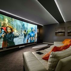 a living room with a large screen tv and couches in front of the television