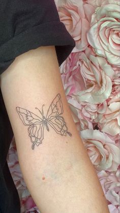 a woman's arm with a small butterfly tattoo on the left side of her arm