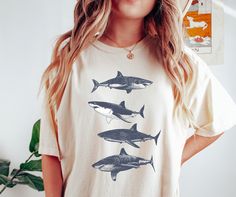 The "Sharks Comfort Colors Shirt For Shark  Lover" is a stylish and comfortable tee, perfect for shark enthusiasts. With its captivating design and soft fabric, it's the ideal summer outfit for beach days. Show your love for sharks while staying comfy and trendy with this must-have shirt. - Comfort Colors C1717 Shirts - Shirt sizes are unisex, please refer to sizing chart in listing photos - 100% ring-spun cotton - Color blast effect will vary on every shirt. We cannot guarantee consistency amon Graphic Tee With Shark Design And Crew Neck, White Crew Neck Top With Shark Design, Shark Lover, Shark T Shirt, Ocean Conservation, Shark Week, White Sharks, Spring Color, Comfort Colors Shirt