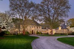 a driveway leading to a large house with trees in the background