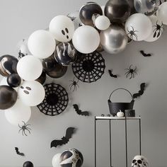 halloween decorations and balloons are hanging on the wall in front of a table with black and white balls