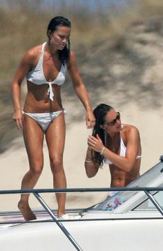 two women in bikinis standing on the back of a boat