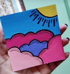 a hand holding up a card with an image of the sun and clouds on it