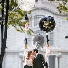 a bride and groom kissing in front of a balloon with the words save the date written on it