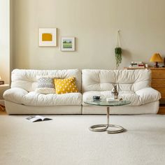 a white couch sitting in a living room next to a table with a cup on it