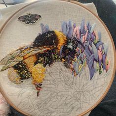 a close up of a person holding a cross stitched object with flowers on it