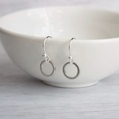 Simple little polished shiny circles dangle from small delicate ball tip ear hooks in a minimalist style.  This hoop / circle dangles about freely from the ear hook.  Super lightweight and easy to wear.  Entire piece is made from silver-plated brass unless you choose to upgrade your HOOKS to .925 sterling silver.. Also in rose gold: https://www.etsy.com/listing/166233096/rose-gold-circle-earrings-tiny-little I will also include a little pair of clear rubber stoppers that you can use for secure wear of your earrings. { M e a s u r e m e n t s } VERY SMALL! Entire length of earring from where inserted into piercing is approx 3/4 inch {19mm}. At its widest point, the earring circle diameter measures approx 1/4 inch {7mm}. Please be certain to view ALL of my photos and always double check meas Gold Knot Earrings, Rose Gold Circle, Gold Circle Necklace, Jewelry Delicate, Circle Ring, Knot Earrings, Style Minimaliste, Bar Earrings, Ear Hook