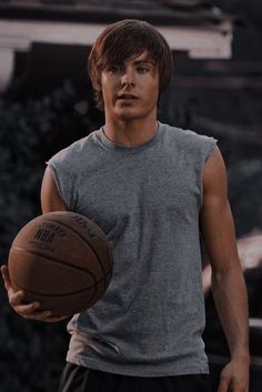 a man holding a basketball in his right hand and looking at the camera with an intense look on his face