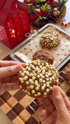 a person holding up a cookie with nuts on it in front of some other cookies