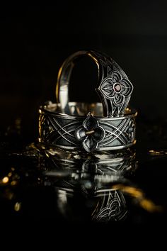 a silver ring sitting on top of a reflective surface