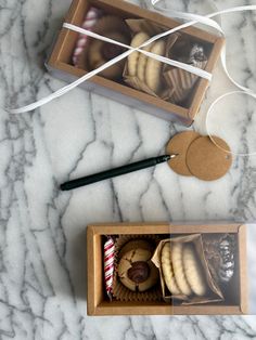 two boxes filled with cookies on top of a marble counter