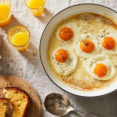 eggs are in a bowl on a table next to toast and orange juice