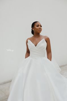 a woman in a white wedding dress poses for the camera