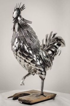 a metal rooster statue sitting on top of a white tablecloth covered table next to a wooden block