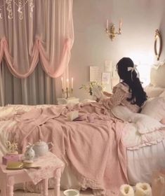 a woman sitting on top of a bed next to a chandelier and table