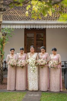 a group of women standing next to each other in front of a building with flowers