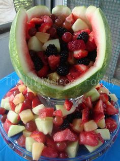 two watermelon halves filled with fruit on top of a blue table