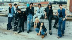 a group of young people sitting on top of a roof next to each other in front of a city skyline