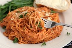 a white plate topped with spaghetti and bread