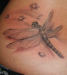 a woman's stomach with a dragonfly tattoo on the side of her belly